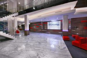 a lobby with red chairs and a large screen at ASTON Lampung City Hotel in Bandar Lampung