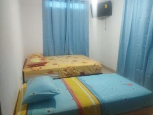 2 camas individuales en una habitación con cortinas azules en Bread Fruit Lodge, en San Andrés