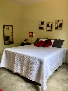 um quarto com uma grande cama branca com almofadas vermelhas em Sítio Primavera em Ipueiras