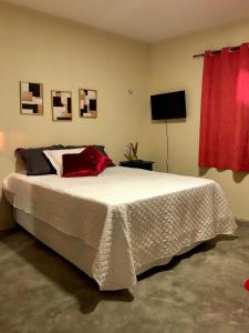 a bedroom with a large white bed with red pillows at Sítio Primavera in Ipueiras
