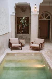 een zwembad met groen water op een binnenplaats met twee stoelen bij Riad Le Sable Vert in Marrakesh