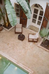 een patio met 2 stoelen en een zwembad bij Riad Le Sable Vert in Marrakesh