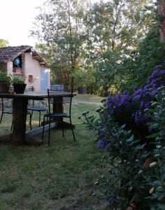 una mesa de picnic en el patio trasero de una casa con flores púrpuras en Cadelbuja, en Canelli