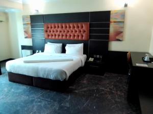a bedroom with a large bed with a red headboard at Desikok Royal Hotel LTD in Port Harcourt