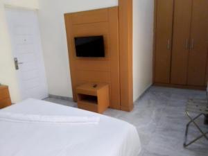 1 dormitorio con 1 cama, TV y armario en Desikok Royal Hotel LTD, en Port Harcourt