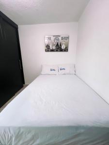 - un lit blanc dans une chambre blanche avec une photo sur le mur dans l'établissement Benavente, Casa hogareña para familias grandes, à Tehuacán