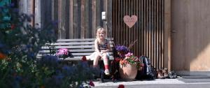 Ein kleines Mädchen auf einer Bank mit Blumen in der Unterkunft Bio Ferienbauernhof Greber in Schwarzenberg im Bregenzerwald