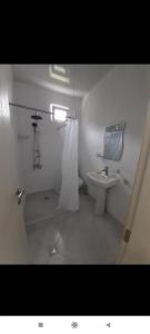 a small white bathroom with a sink and a mirror at Geno Guest House in Kvariati