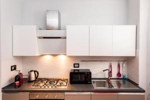 uma cozinha com armários brancos e um forno com placa de fogão em Tony House em Omegna