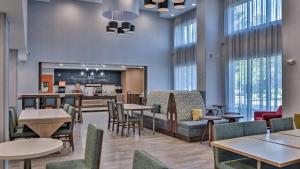 a restaurant with tables and chairs and a bar at Hampton Inn & Suites Keene in Keene