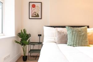 ein Schlafzimmer mit einem weißen Bett und einer Pflanze in der Unterkunft Stylish 1-Bed Flat in Liverpool by 53 Degrees Property, Ideal for Business & Long-Term Stays! in Liverpool