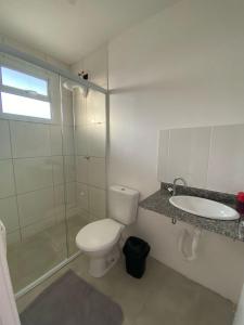 a white bathroom with a toilet and a sink at Casa em Condomínio Fechado in Pelotas