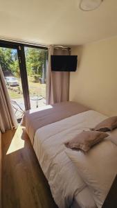 1 dormitorio con 1 cama grande y ventana grande en Ketrawe Lodge, en Pucón