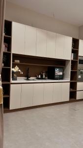 a kitchen with white cabinets and a microwave at شالية سَال الفندقي in Buraydah