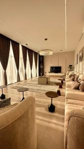 een grote woonkamer met een bank en tafels bij شالية سَال الفندقي in Buraydah