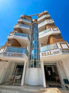 a tall white building with a sign that reads real inn at Hotel Caribe Real Inn in Santa Marta