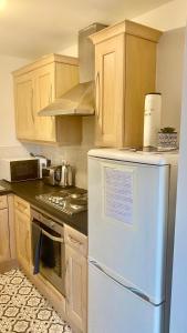 een keuken met een witte koelkast en houten kasten bij Spacious 1 Bedroom Apartment In Wigan in Shevington