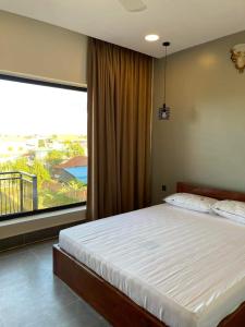 a bedroom with a bed and a large window at NataRiya Villa in Siem Reap