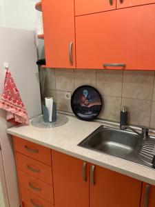 a kitchen counter with a sink and orange cabinets at Tea in Sremska Mitrovica