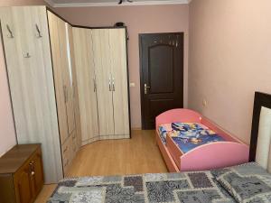 een slaapkamer met een bed, een wieg en een kast bij Comfortable 2-BR for 5 in Tirana