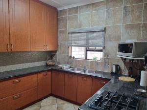 a kitchen with wooden cabinets and a sink and a microwave at Spacious apartment with lovely sea view in Hibberdene