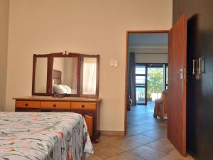 a bedroom with a bed and a dresser with a mirror at Spacious apartment with lovely sea view in Hibberdene