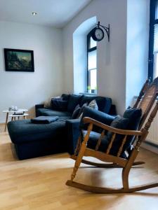 ein Wohnzimmer mit einem blauen Sofa und einem Stuhl in der Unterkunft Ferienwohnung am Rabenauer Grund in Freital