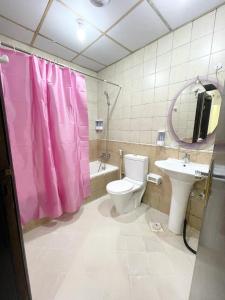 a bathroom with a pink shower curtain and a toilet at Premier Serviced Males Hostel in Dubai