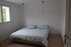 un letto in una camera bianca con finestra di Maison en Normandie a Londinières