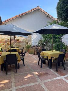 2 mesas y sillas con sombrillas en un patio en Hostería Doña Vivi, en Barichara