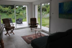 a living room with chairs and a table and sliding glass doors at Maison en Normandie in Londinières +1 photo