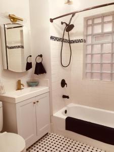 a white bathroom with a tub and a sink at Modern Logan Square 1 bedroom Flat in Chicago