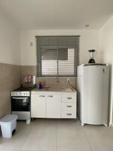 La cuisine est équipée d'un réfrigérateur blanc et d'un évier. dans l'établissement Casa em Condomínio Fechado, à Pelotas