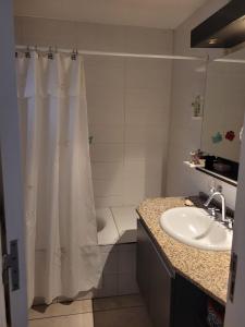 baño con cortina de ducha blanca y lavamanos en La Gringa: Casa amplia, luminosa, dos habitaciones en Las Heras