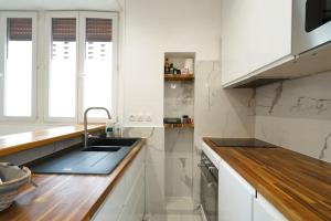 a white kitchen with a sink and a counter at studio lumineux à BORDEAUX CHARTRONS / JARDIN PUBLIC in Bordeaux