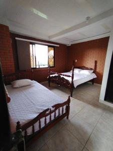 a bedroom with two beds and a window at Hermosa finca de recreo Pereira in Pereira