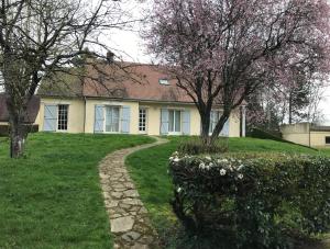 una casa amarilla con un árbol y una pasarela en GITE Thiron Gardais LA COUR aux PAUVRES en Thiron-Gardais