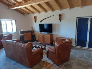 a living room with leather chairs and a flat screen tv at Monte Santiago in Fronteira