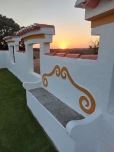 een wit hek met een zonsondergang op de achtergrond bij Monte Santiago in Fronteira