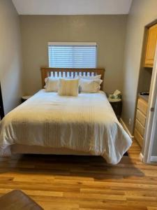 1 dormitorio con 1 cama blanca y suelo de madera en Oceanview Cabin 21, Jacuzzi, Large Deck W View, en Smith River
