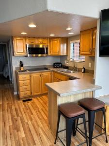 una cocina con armarios de madera y una isla de cocina con taburetes en Oceanview Cabin 21, Jacuzzi, Large Deck W View, en Smith River