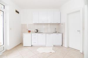 a white kitchen with white cabinets and a rug on the floor at Apartments Savić in Herceg-Novi
