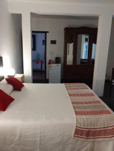 1 dormitorio con 1 cama blanca grande con almohadas rojas en Posada La Casona en Mar de las Pampas