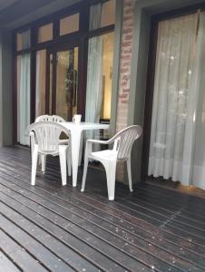 マール・デ・ラス・パンパスにあるPosada La Casonaの白いテーブルと椅子2脚付きのポーチ