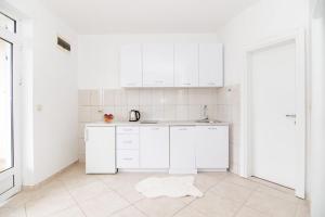 a white kitchen with white cabinets and a rug on the floor at Apartments Savić in Herceg-Novi