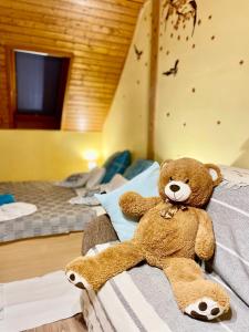 a teddy bear sitting on a bed in a room at Marta Guest House in Gyenesdiás