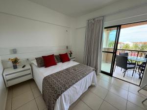 a bedroom with a bed with red pillows and a balcony at Apartamento Beverly Hills - Próximo ao Beach Park in Aquiraz
