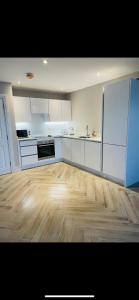 a kitchen with white cabinets and a wooden floor at Luxurious Beach Front Apartment in Portrush in Portrush