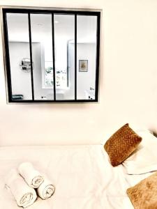 a mirror above a white couch with towels on it at Appartement Cosy centre-ville in Ribérac