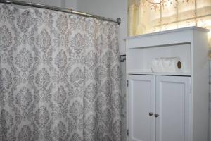 baño con cortina de ducha y armario blanco en Belle Zoon Villa, en Cap Estate